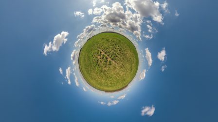 green tiny planet in blue sky with beautiful clouds with transformation of spherical panorama 360 degrees. Curvature of space.