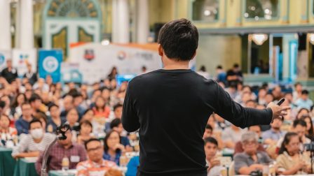 Rear view of Asian Speaker with casual suit standing and giving the knowledge